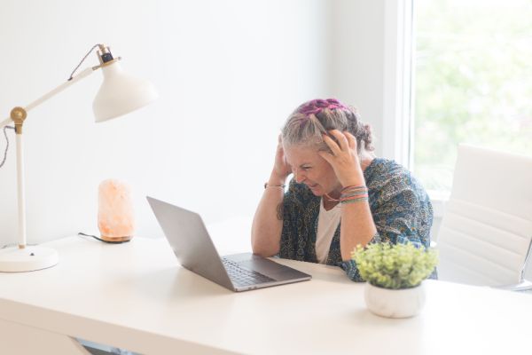 Stressed woman holding her head at a laptop