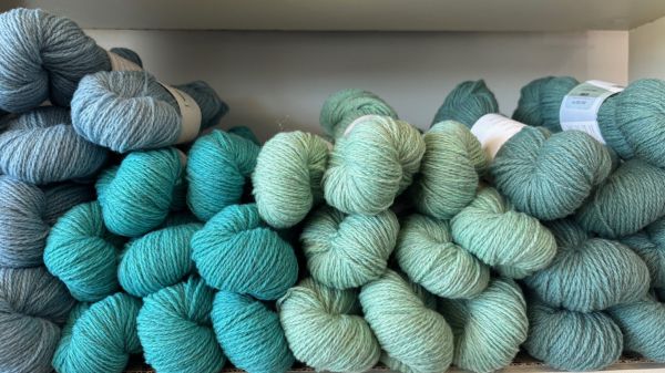 Yarn skeins neatly stacked on a shelf by shade