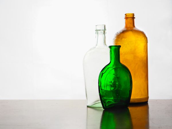 Trois bouteilles en verre colorées : transparente, verte et ambrée